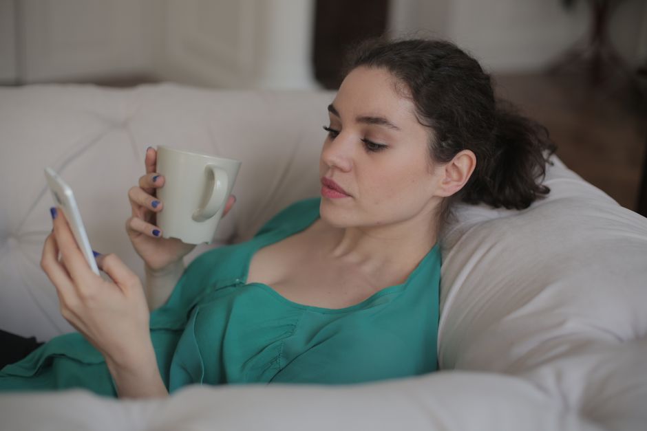 ソファでスマートフォンからメッセージを送る女性